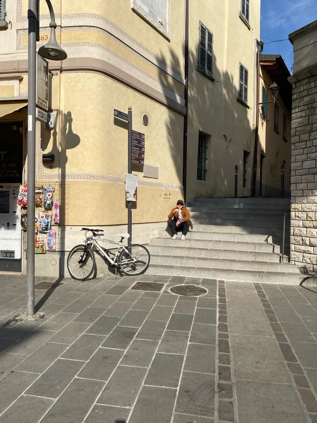 Ecke in der Iseo Altstadt mit Wegweiser, abgestelltem Fahrrad und alten Häusern in der Sonne