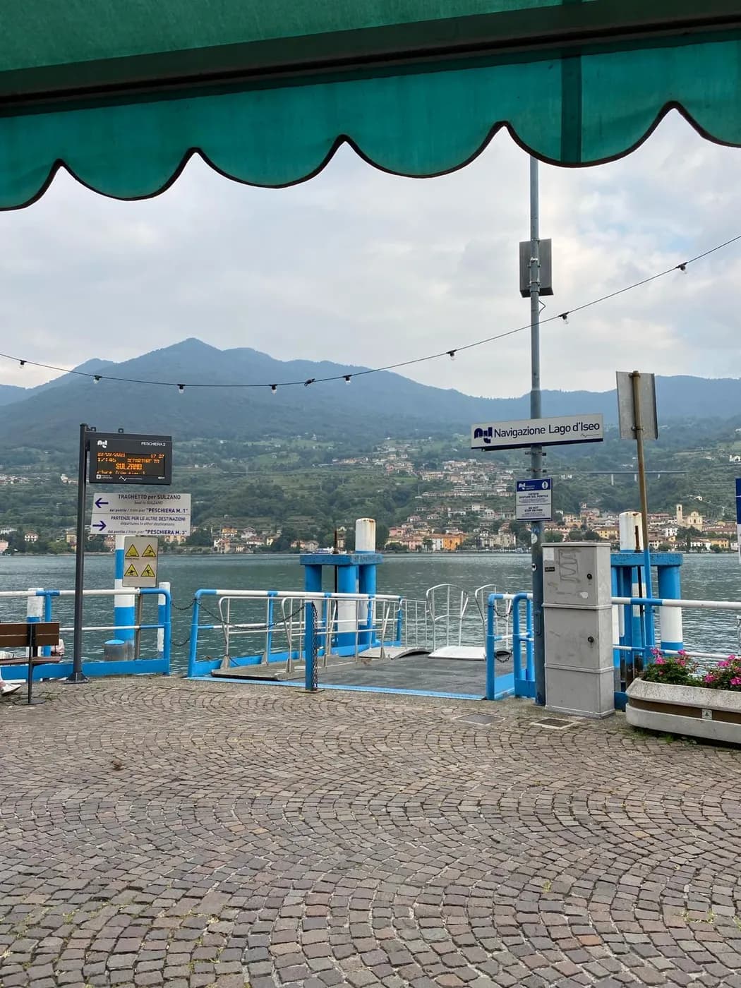 Fähranleger von Navigazione Lago d'Iseo am Hafen mit Anzeigetafel und Blick auf Monte Isola