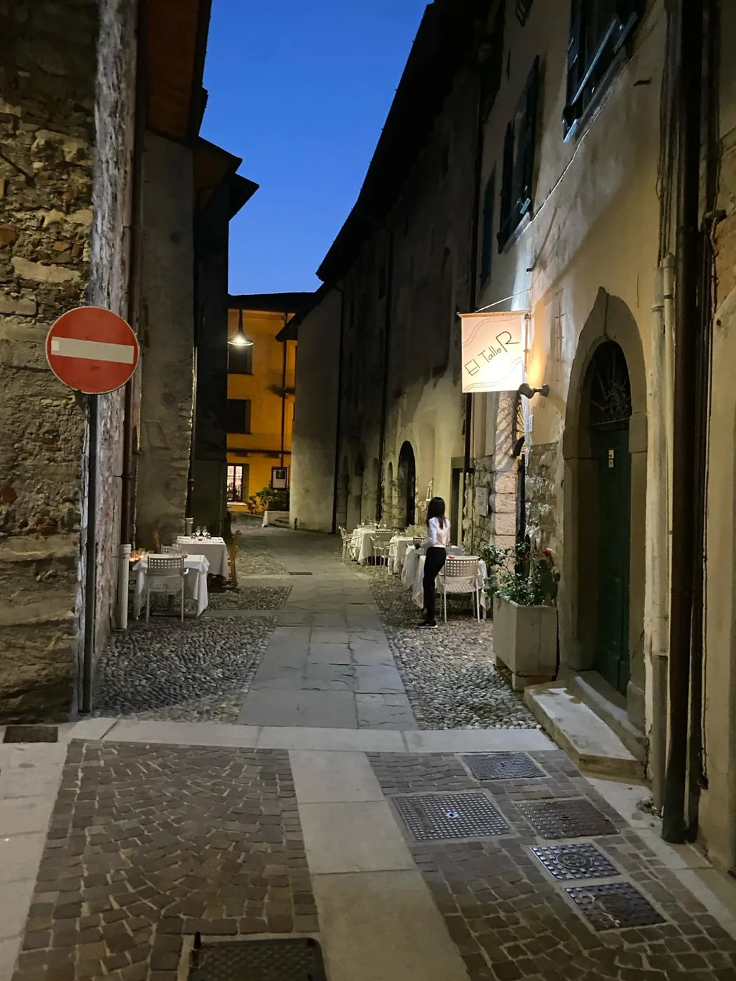 Mittelalterliche Gasse in Iseo mit gedeckten Restauranttischen in der Abenddämmerung